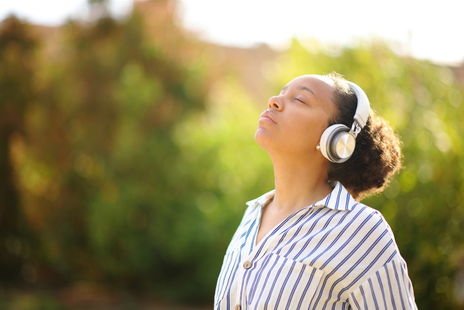 Woman meditating outdoors wearing headphones